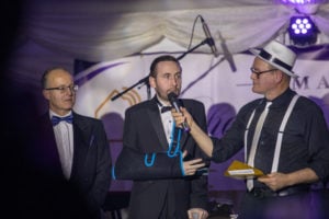 Three men on a stage at a charity event