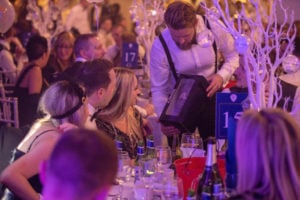 A man holding a box containing champagne at a charity event